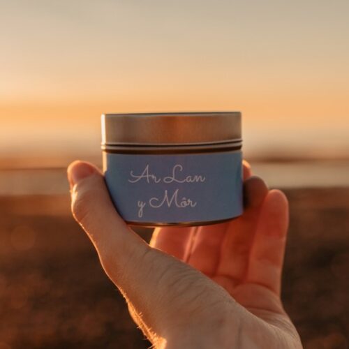 Ar lan y mor mini tin candle in hand with sunset